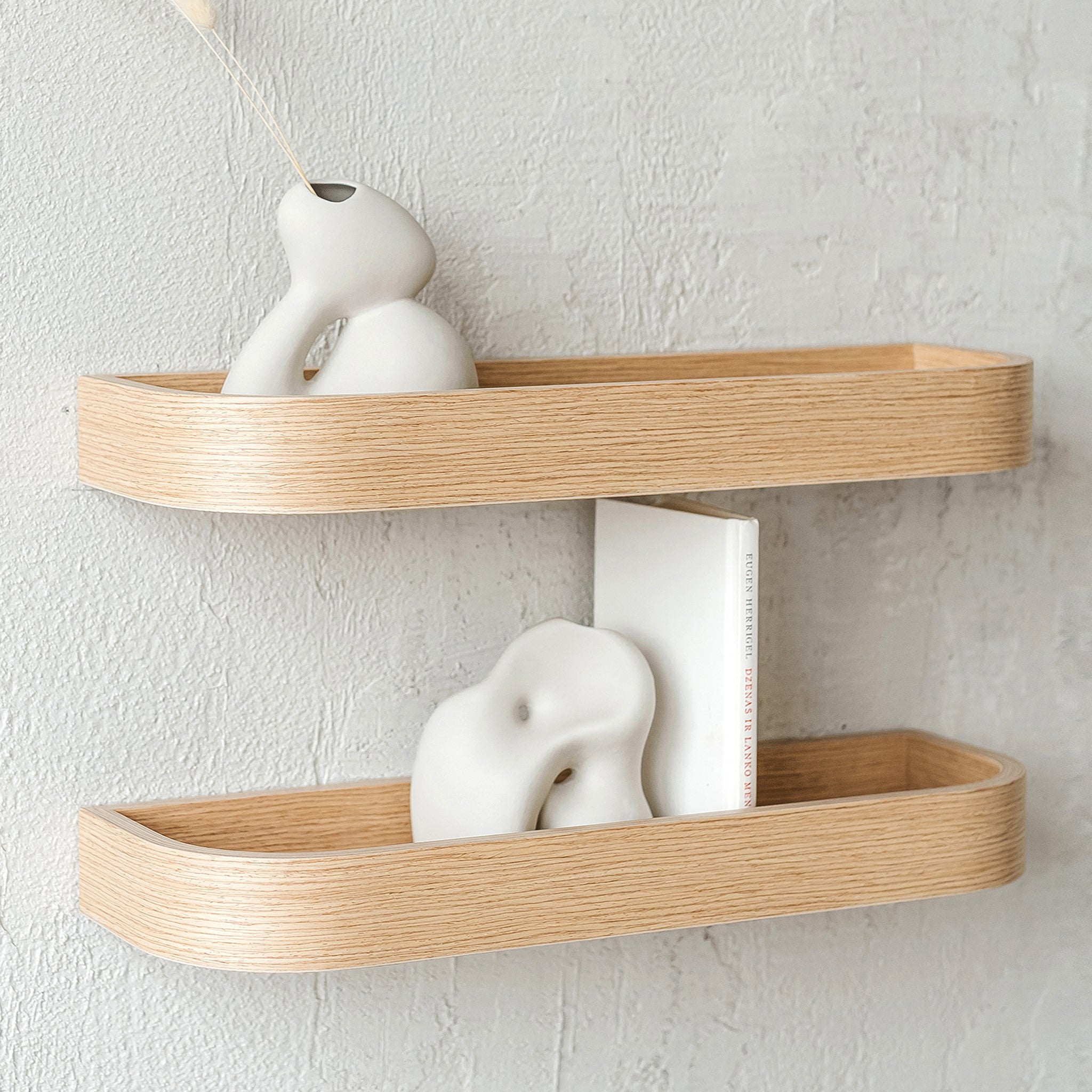 Natural oak wood floating wall shelf holding small decorative plants and picture frames in modern home
