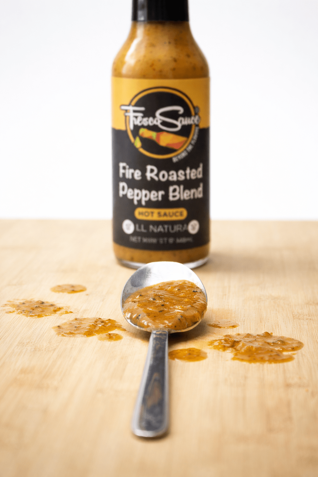 Fire Roasted Pepper Blend Hot Sauce in a glass bottle with fresh jalapenos — view 4