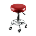 Two burgundy PU leather swivel salon stools with steel frames and rolling casters