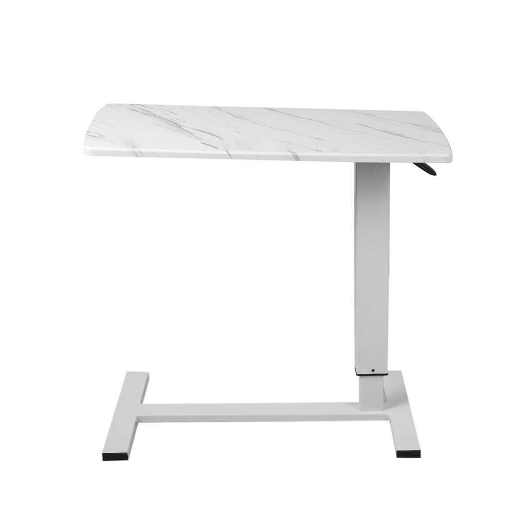 Marbled white adjustable standing desk with steel frame and hidden wheels next to a modern sofa