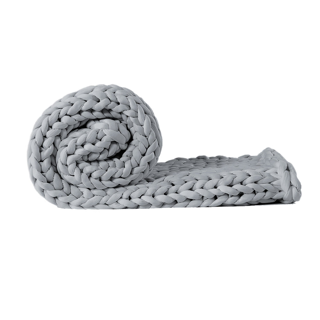 Chunky grey knitted weighted blanket folded neatly on a bed for anxiety relief and restful sleep