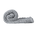Chunky grey knitted weighted blanket folded neatly on a bed for anxiety relief and restful sleep