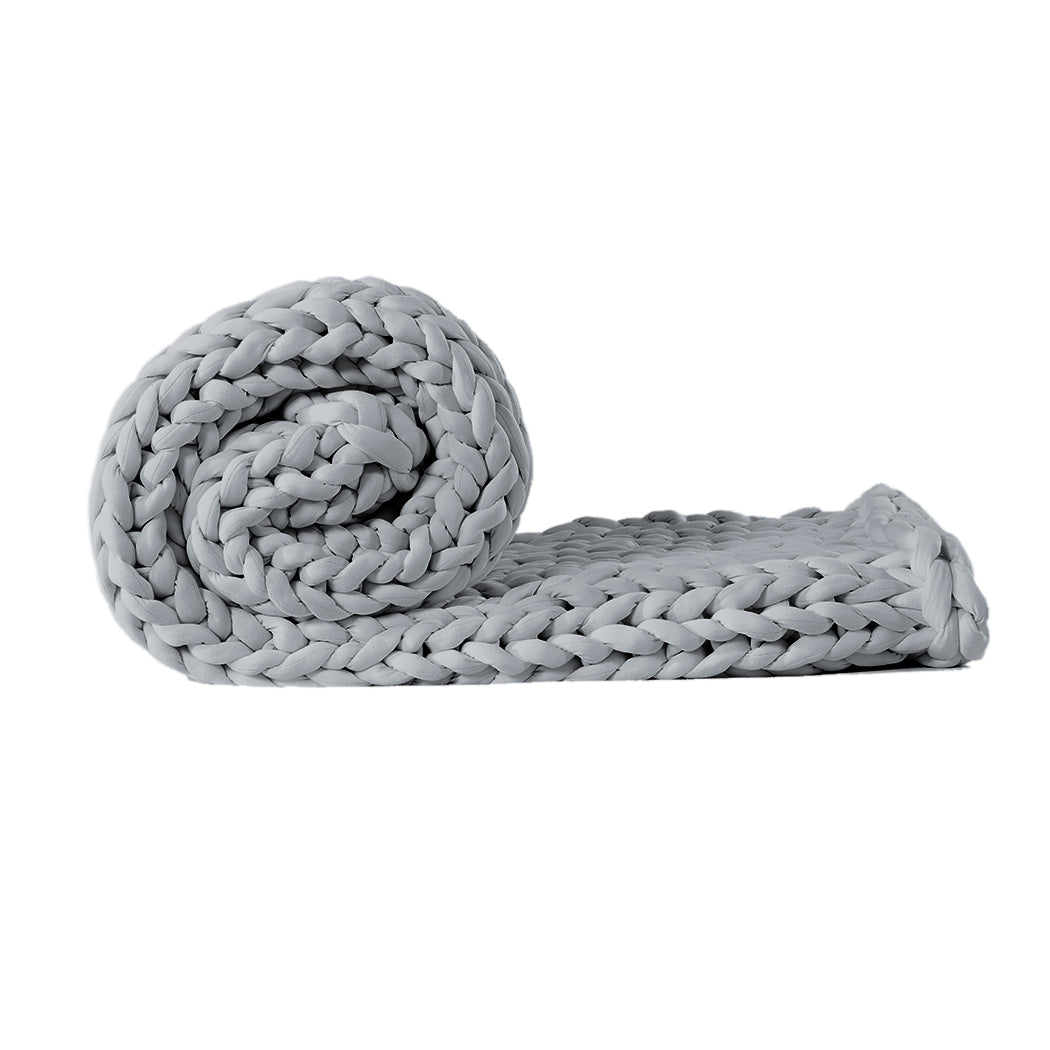 Chunky grey knitted weighted blanket folded neatly on a bed for anxiety relief and restful sleep