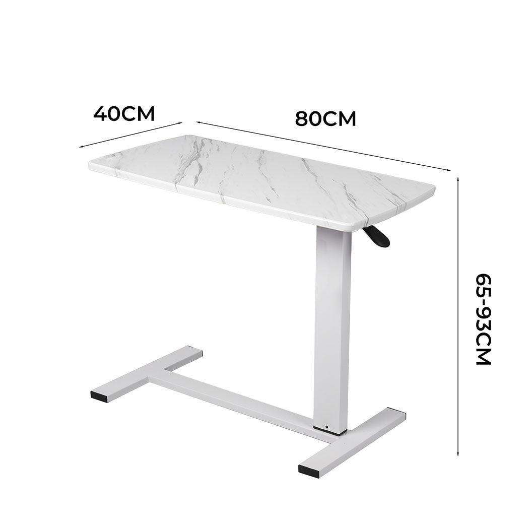 Marbled white adjustable standing desk with steel frame and hidden wheels next to a modern sofa — view 2