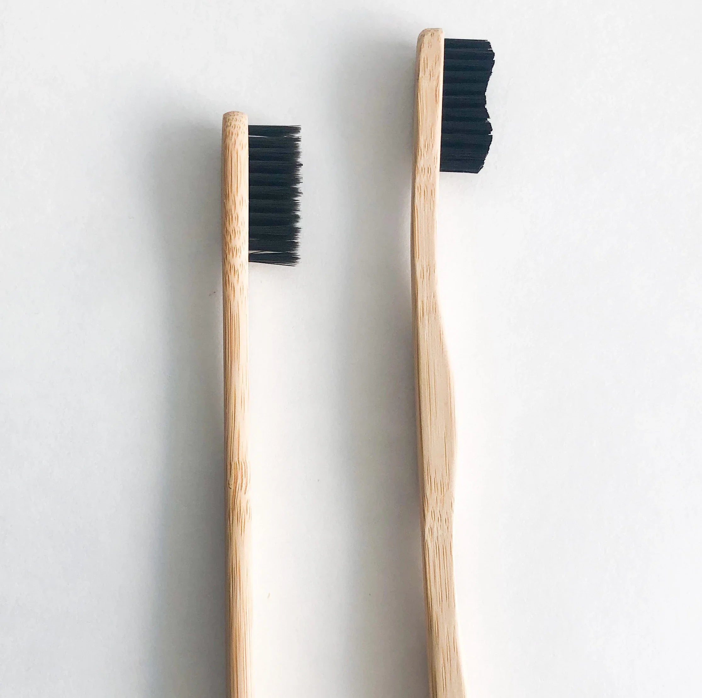 Bamboo charcoal toothbrush with black soft bristles and natural wooden handle on a clean background — view 5