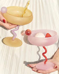 Colorful mouth-blown Jelly Bean cocktail coupe glasses displayed on an elegant festive dining tabletop.