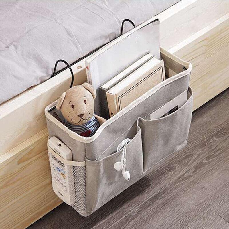 Canvas bedside storage caddy hanging on a bed frame holding books and remote controls — view 3