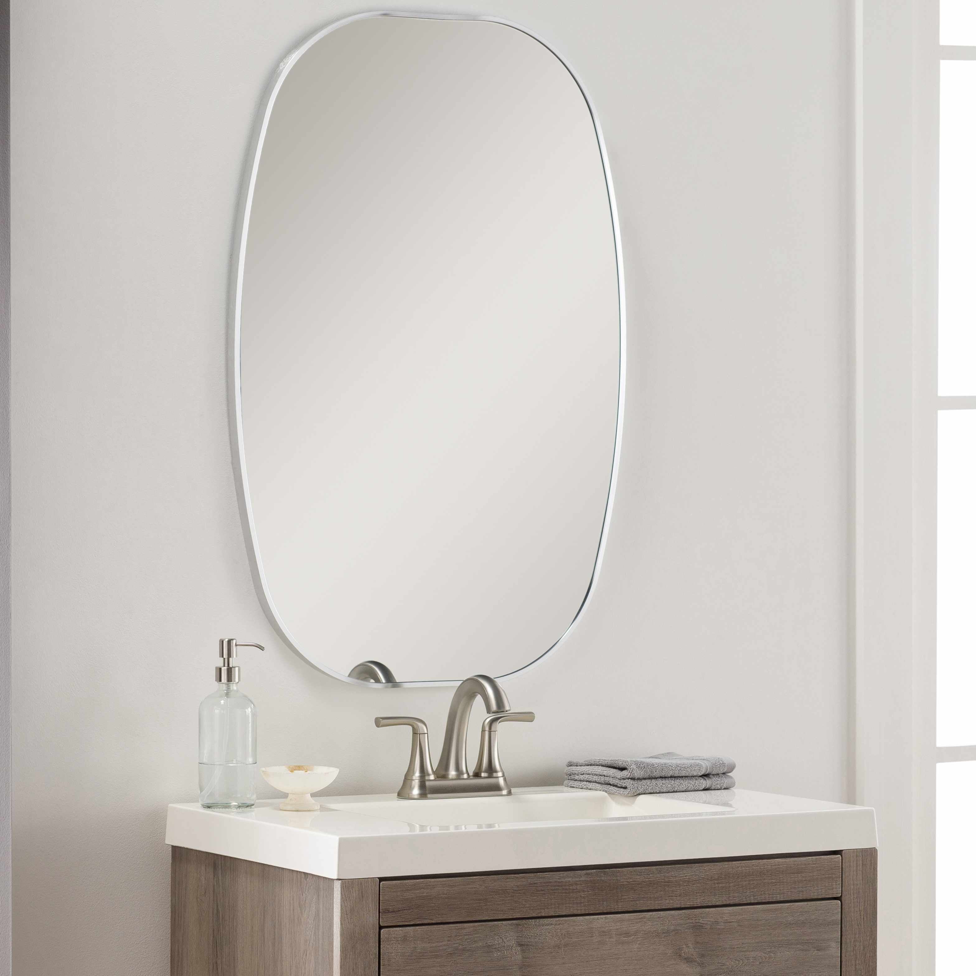 Round contemporary wall mirror with a metallic silver-gray aluminum frame on a blank wall