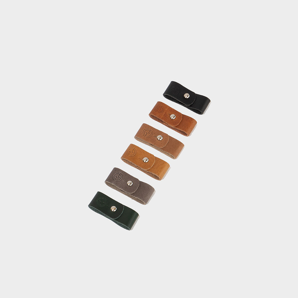 Premium vegetable-tanned leather cord organizer set with metal snap holding a white charging cable — view 2