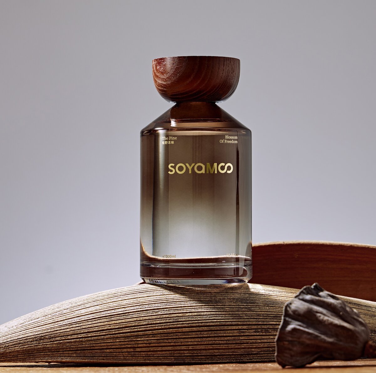 Warm brown angled shoulder glass reed diffuser with wooden cap and luxury woody fragrance