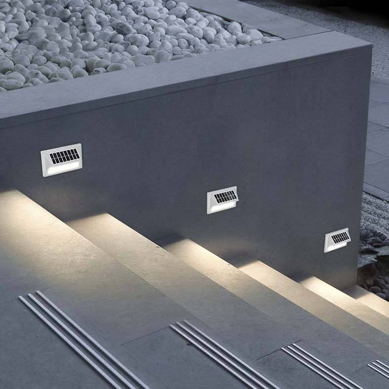 Two black powder-coated aluminum Mesa-100 outdoor solar deck lights illuminating a dark wooden step.