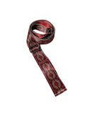 Warm red organic cotton yoga strap with metal D-ring buckles rolled up for studio practice