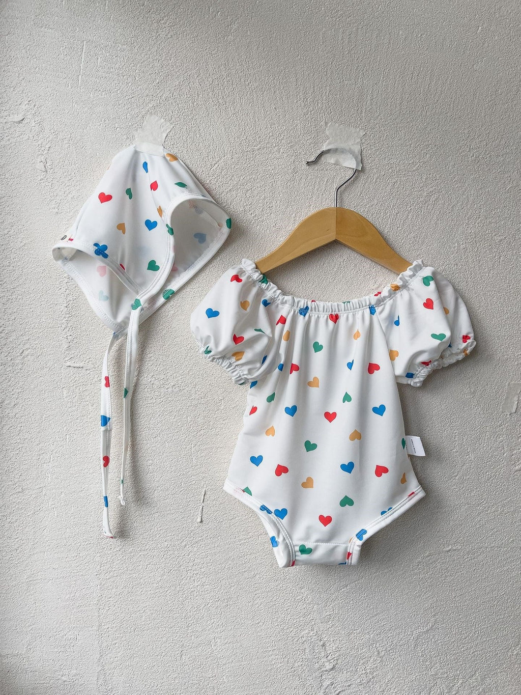 White baby girls one piece swimsuit with red hearts pattern and matching sun protection hat