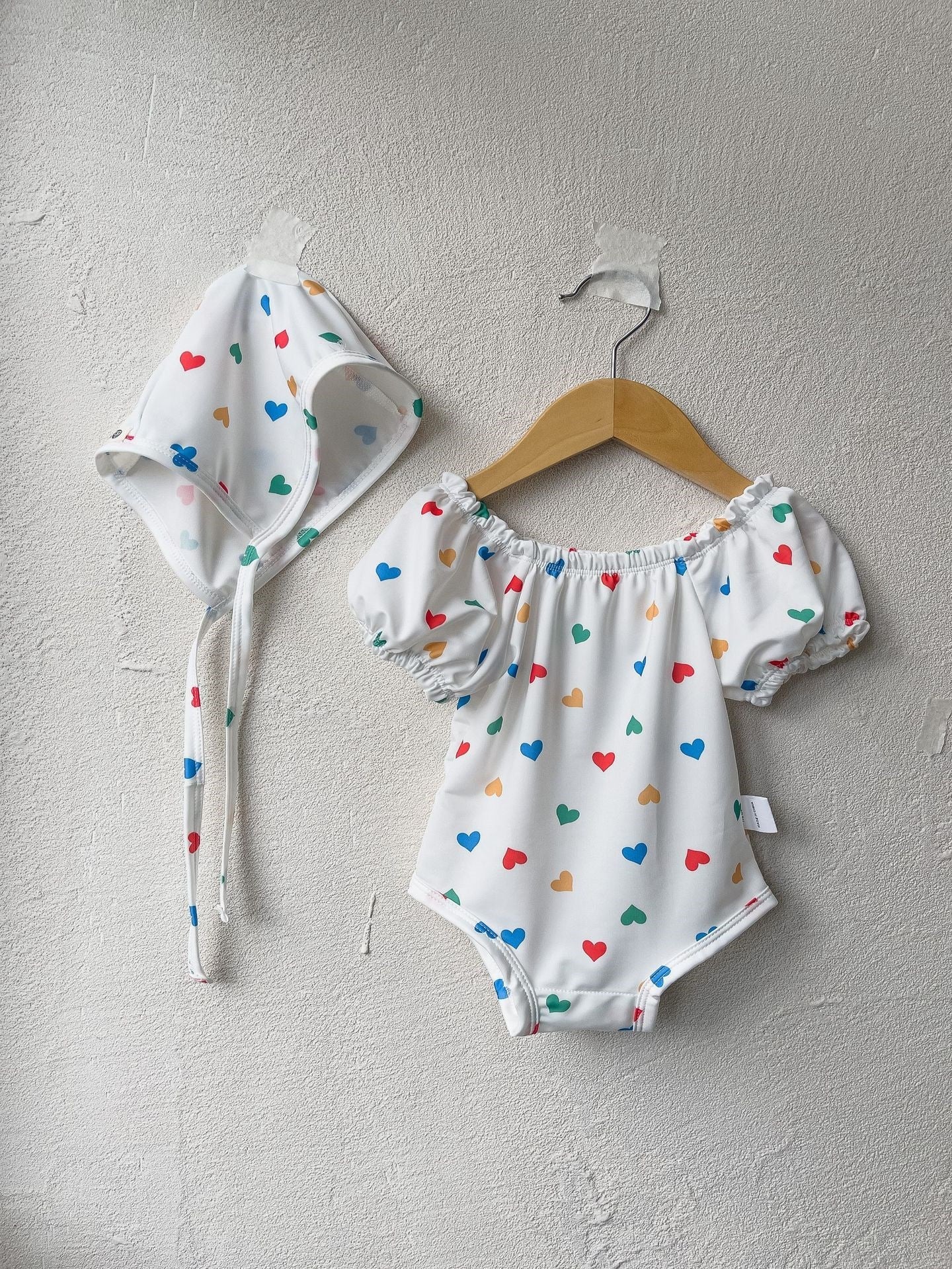 White baby girls one piece swimsuit with red hearts pattern and matching sun protection hat