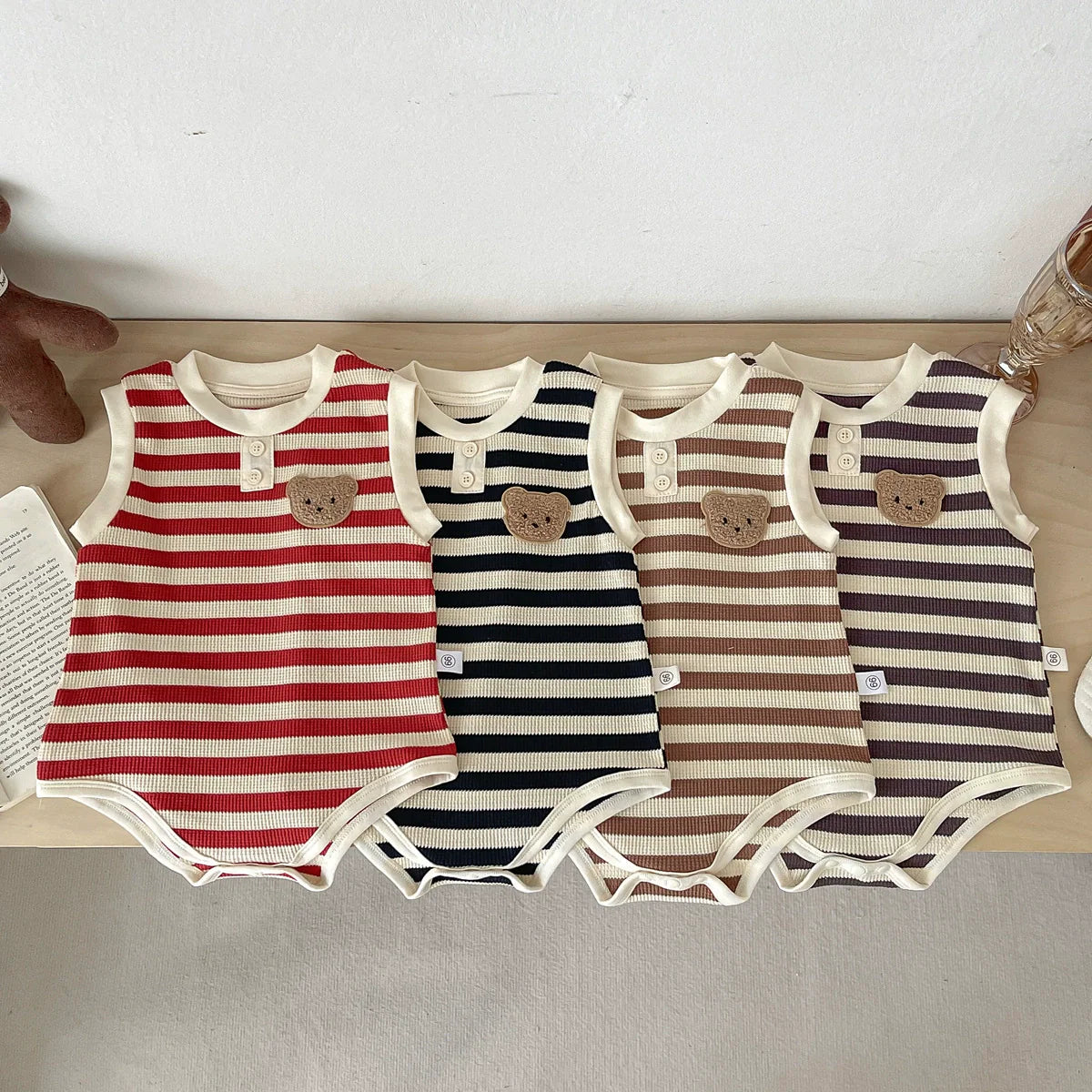 Unisex sleeveless baby bodysuit featuring a striped pattern and teddy bear motif in soft cotton.
