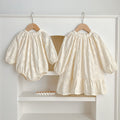 Floral baby girl bodysuit dress in neutral tones with round neckline and snap button bottom closure