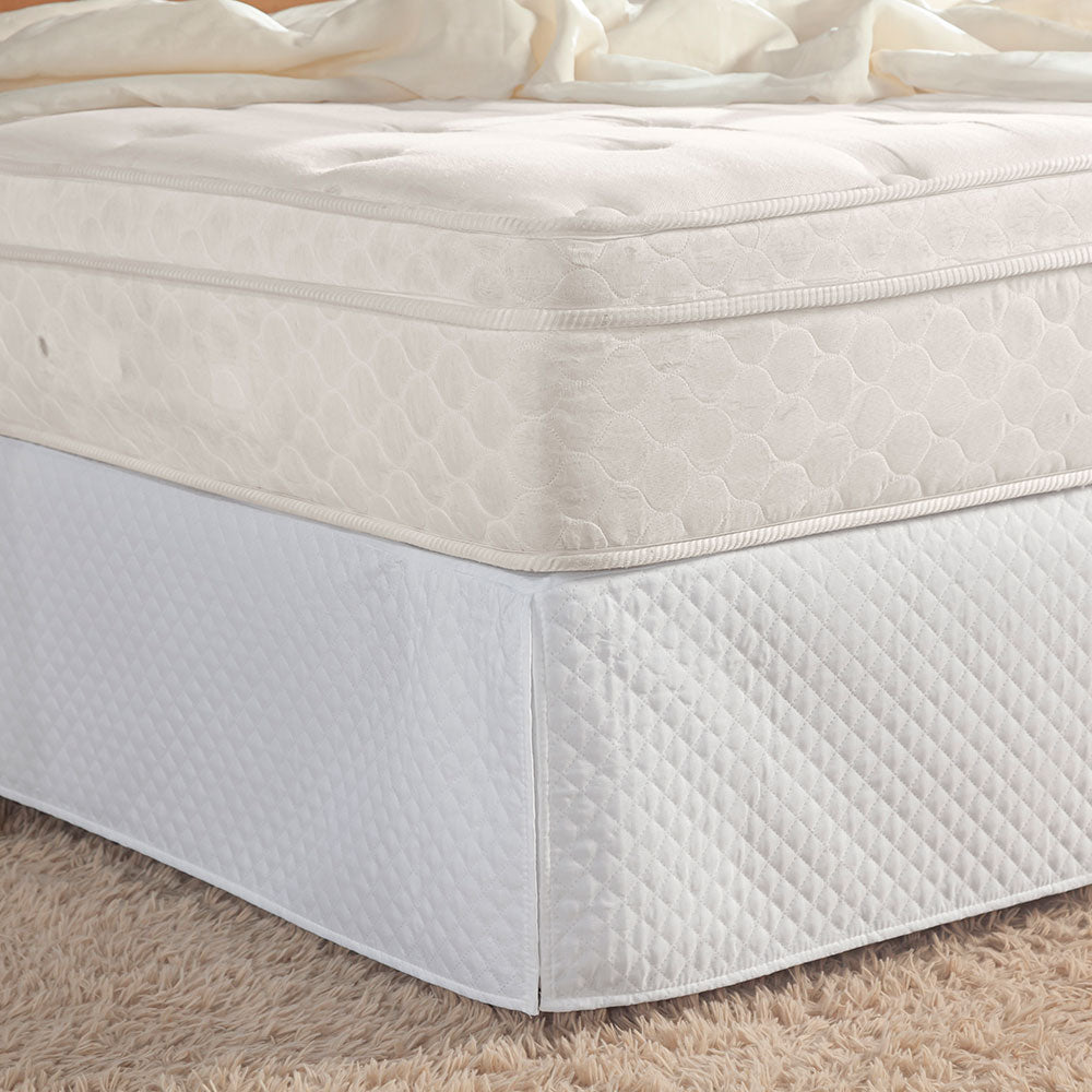 Quilted white full bed skirt with tailored corner pleats covering a standard bedroom box spring — view 3