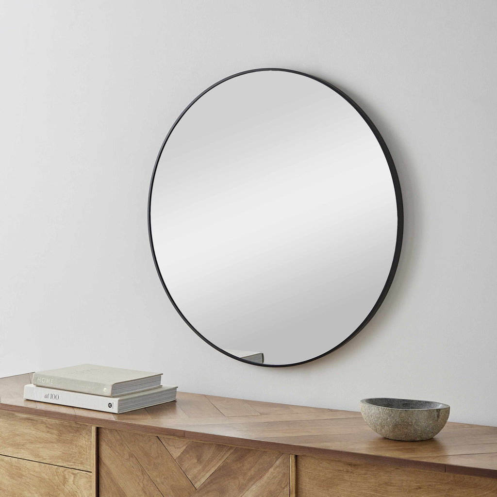 Contemporary round wall mirror with a sleek black aluminum frame, perfect for modern home interiors.
