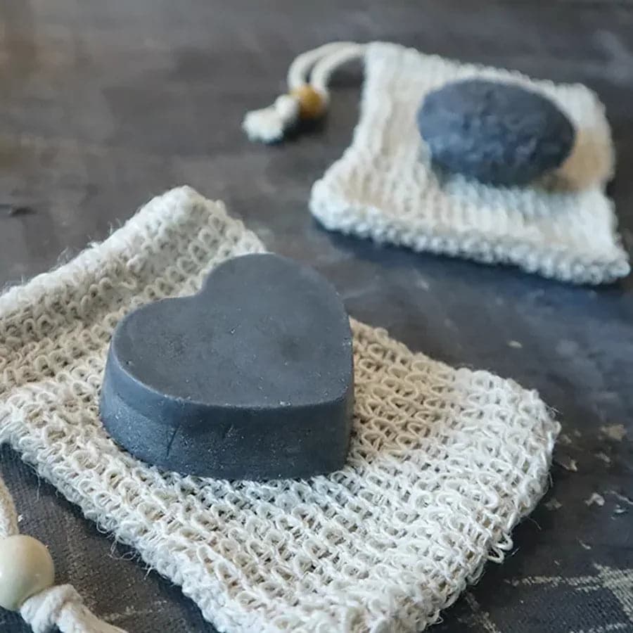 Solid charcoal rebalancing shampoo bar for oily hair placed on a natural wooden soap dish. — view 5