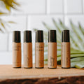 Collection of essential oil rollers with distinct blends infused with crystals in clear glass bottles