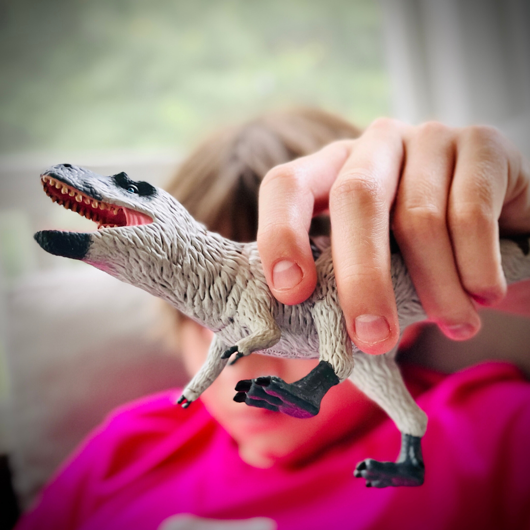 Nanuqsaurus toy dinosaur figure with white feathers and blue-gray skin in a dynamic standing pose — view 2