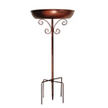 Vintage metal bird bath with copper finish on a sturdy pedestal stand in an outdoor garden