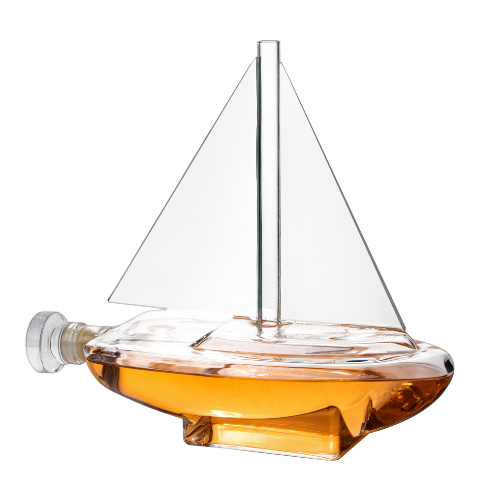 Glass sailboat whiskey decanter with built-in spigot resting on a sturdy wooden display base