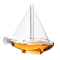 Glass sailboat whiskey decanter with built-in spigot resting on a sturdy wooden display base