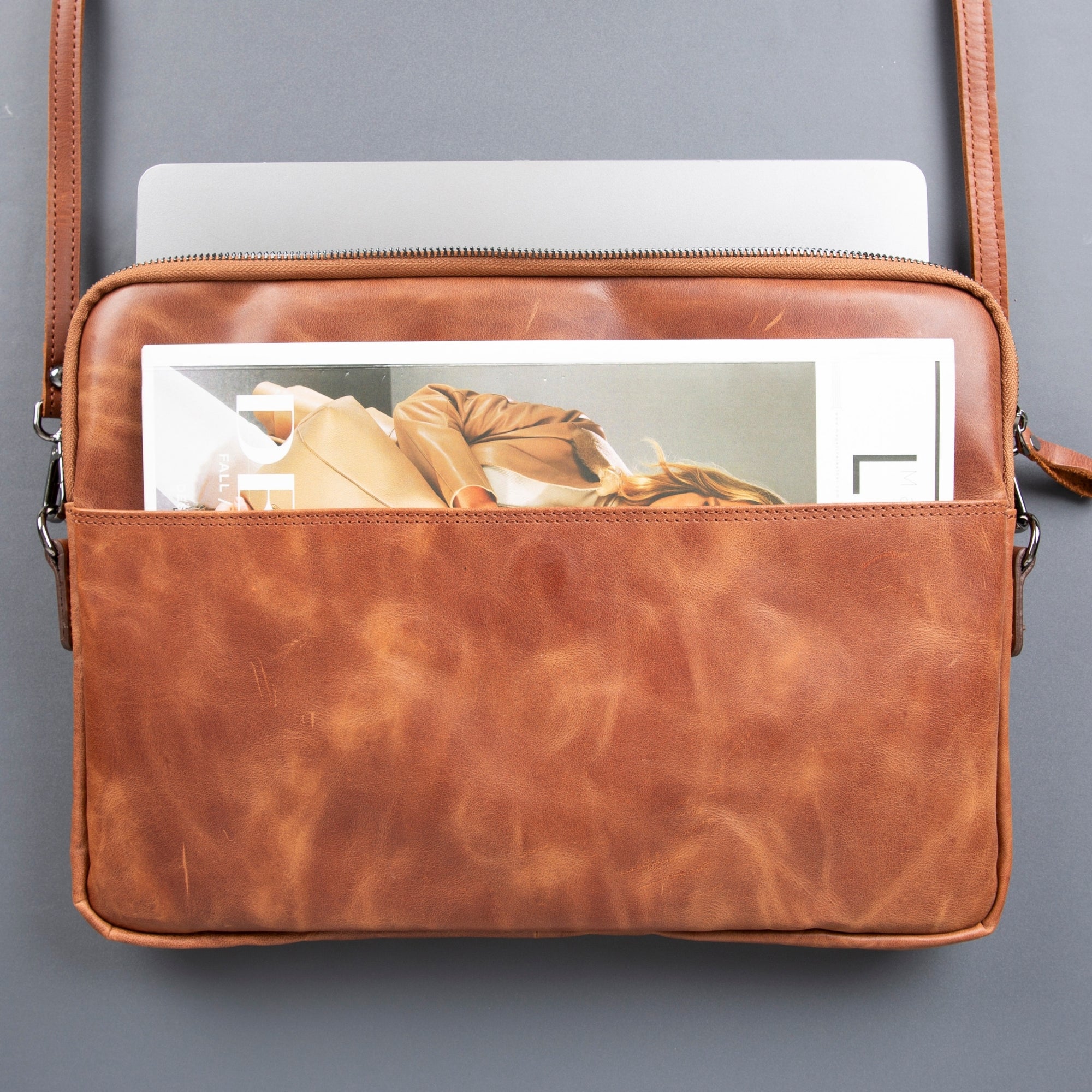 Genuine leather laptop bag with shoulder strap, soft suede interior, and front pocket for professional use.