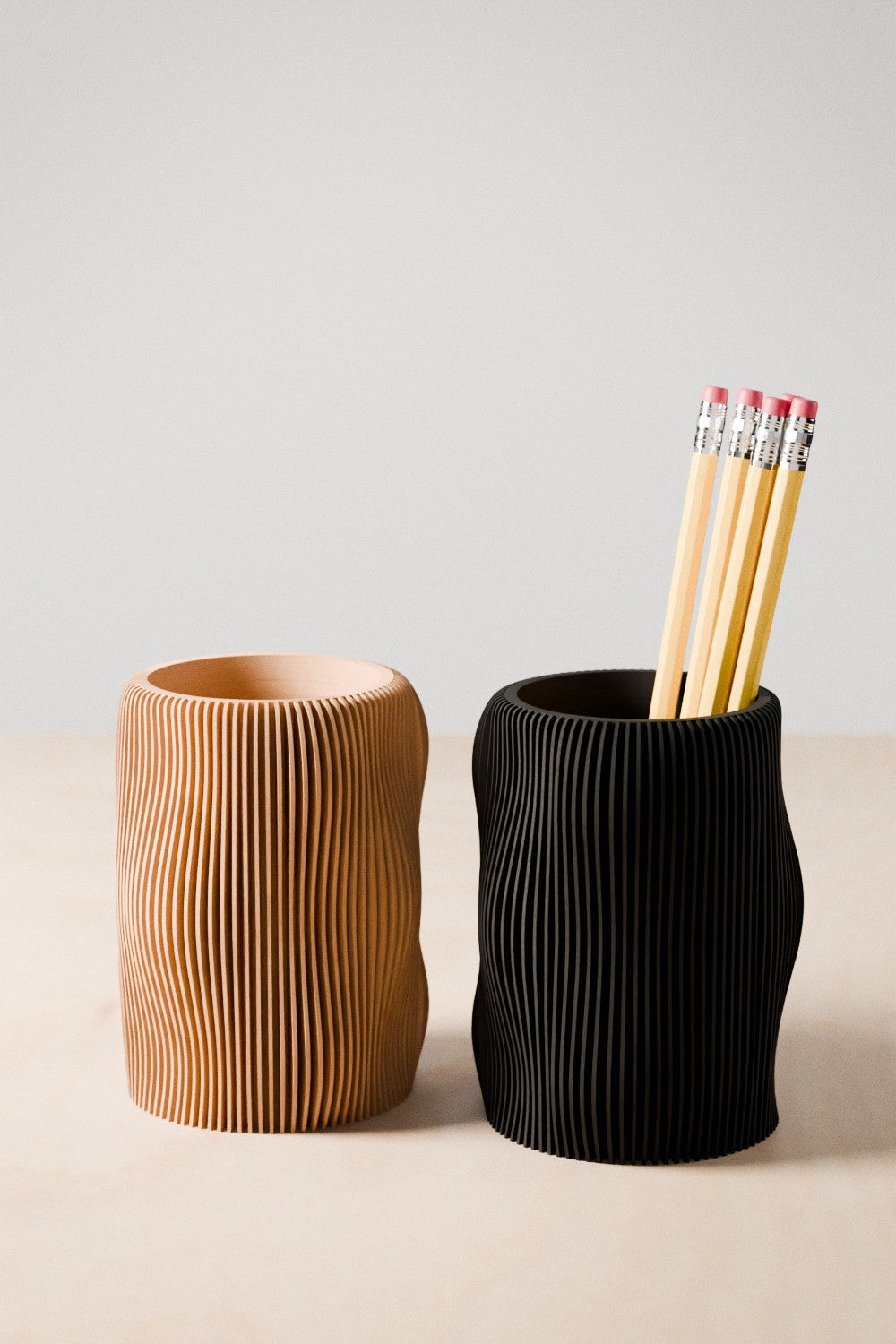 Wavy textured modern pencil holder organizing pens on a desk, made of eco-friendly materials.