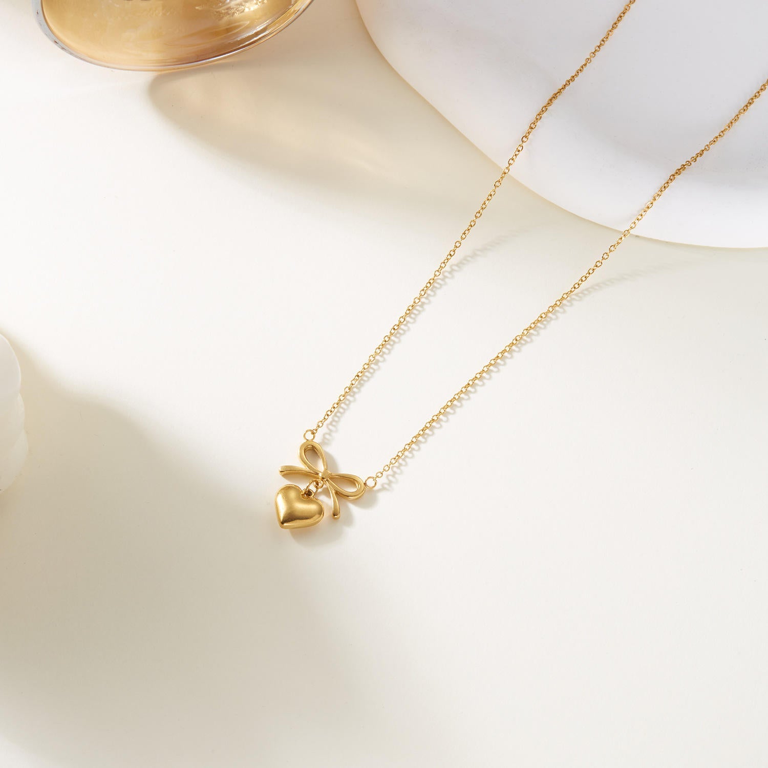 Dainty 18k gold plated bow heart pendant necklace with an adjustable chain on clean background — view 3