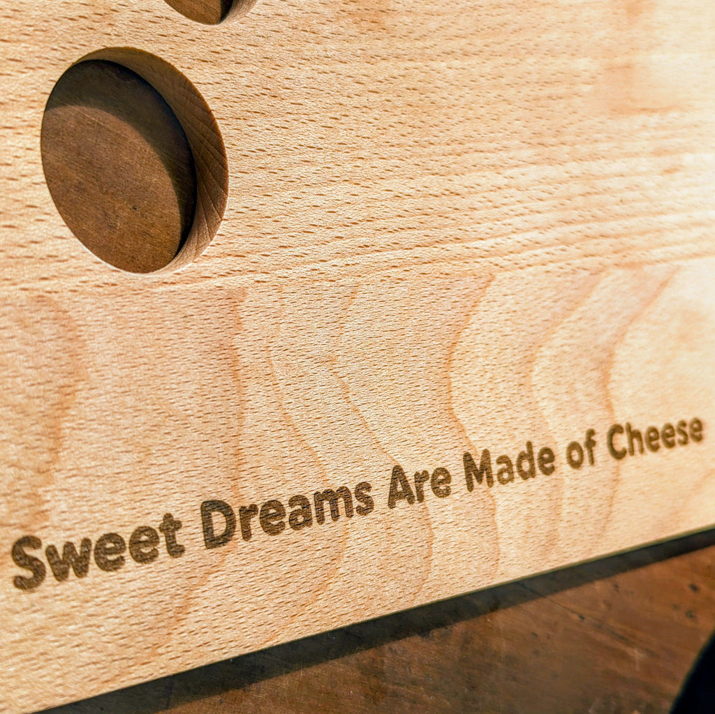 Beech wood cheese board with quirky cutout holes design, resting flat on a table surface — view 3