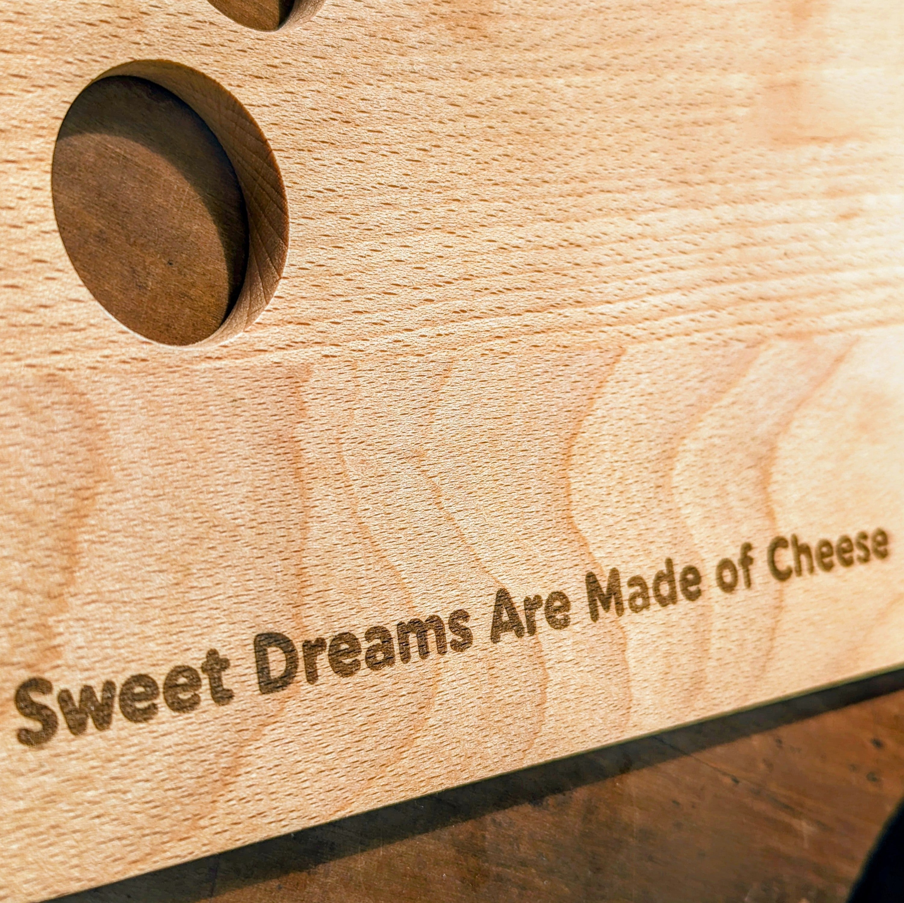 Beech wood cheese board with quirky cutout holes design, resting flat on a table surface — view 3