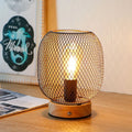 Bronze cage lantern style touch table lamp with wooden base and glowing golden LED bulb