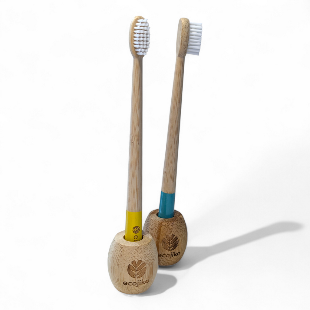 Unwaxed bamboo toothbrush stand on a bathroom counter holding a wooden adult toothbrush — view 2