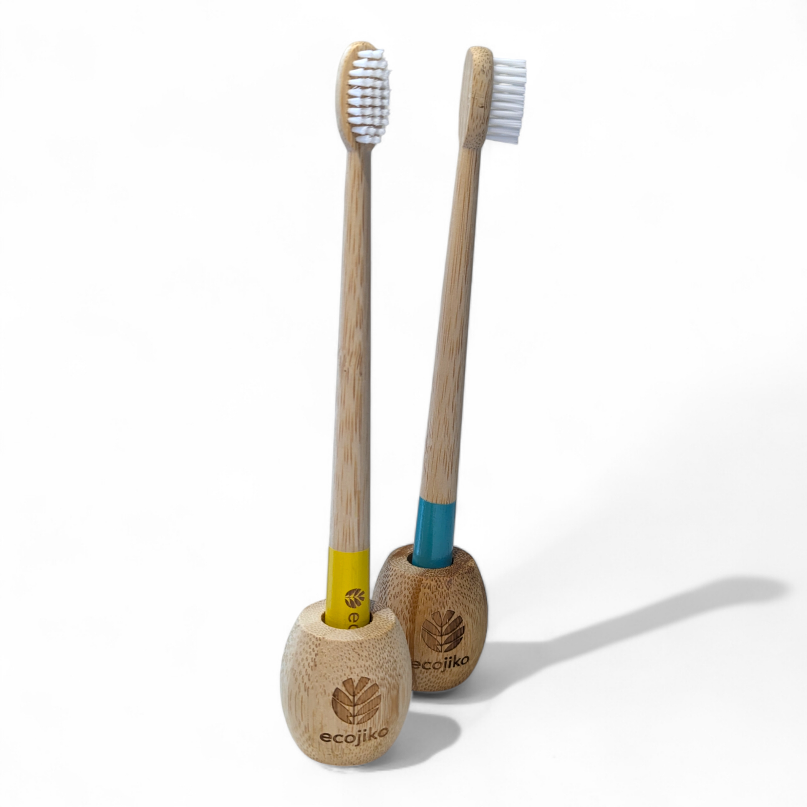 Unwaxed bamboo toothbrush stand on a bathroom counter holding a wooden adult toothbrush — view 2