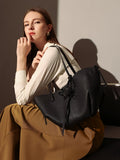 Pebbled leather trapezoid tote bag featuring a sculptural front knot detail and long shoulder straps