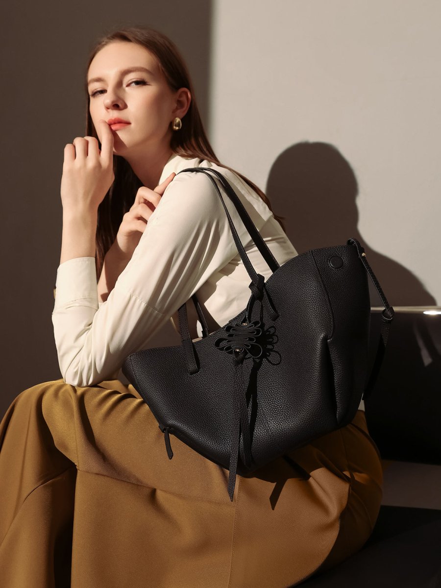 Pebbled leather trapezoid tote bag featuring a sculptural front knot detail and long shoulder straps