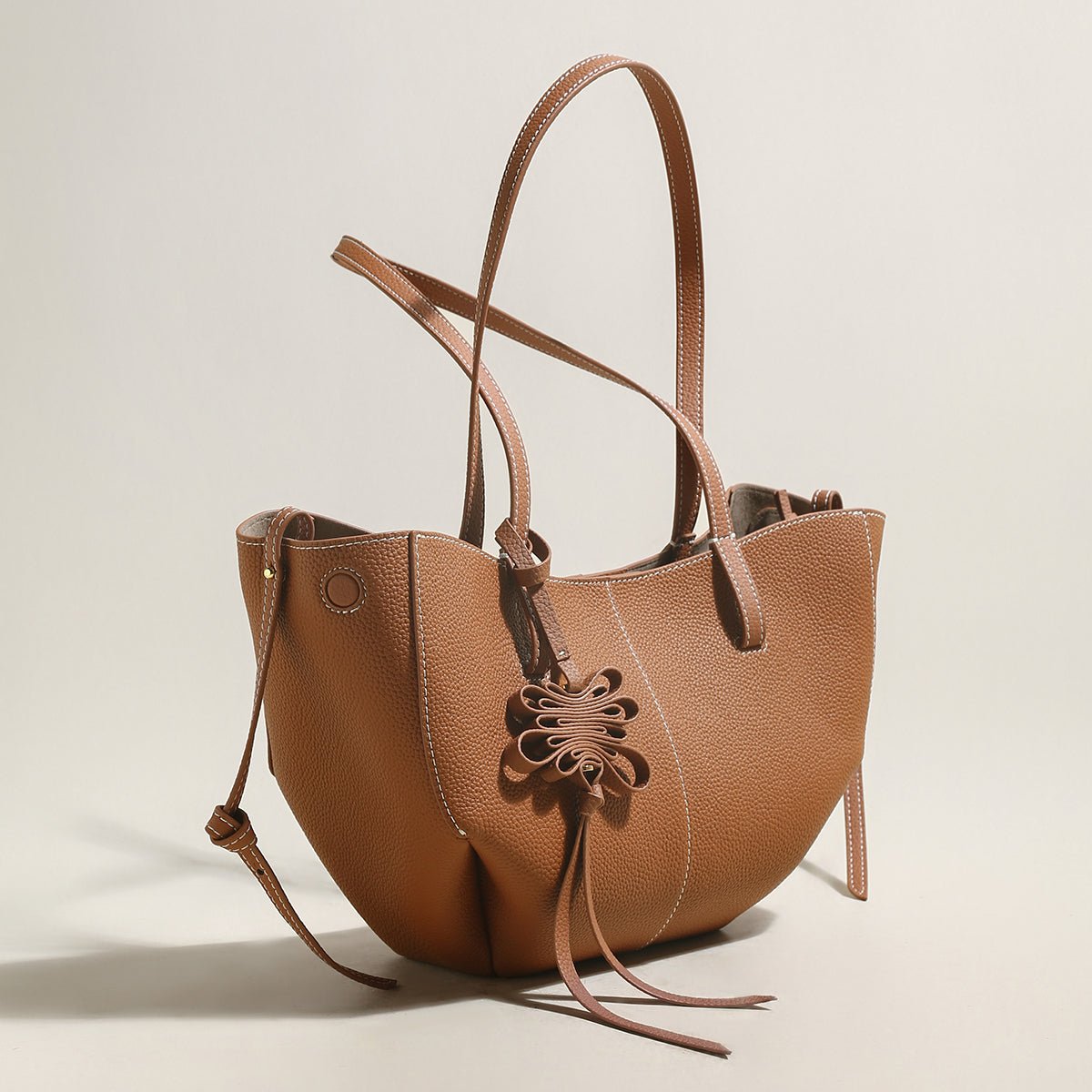 Pebbled leather trapezoid tote bag featuring a sculptural front knot detail and long shoulder straps — view 4