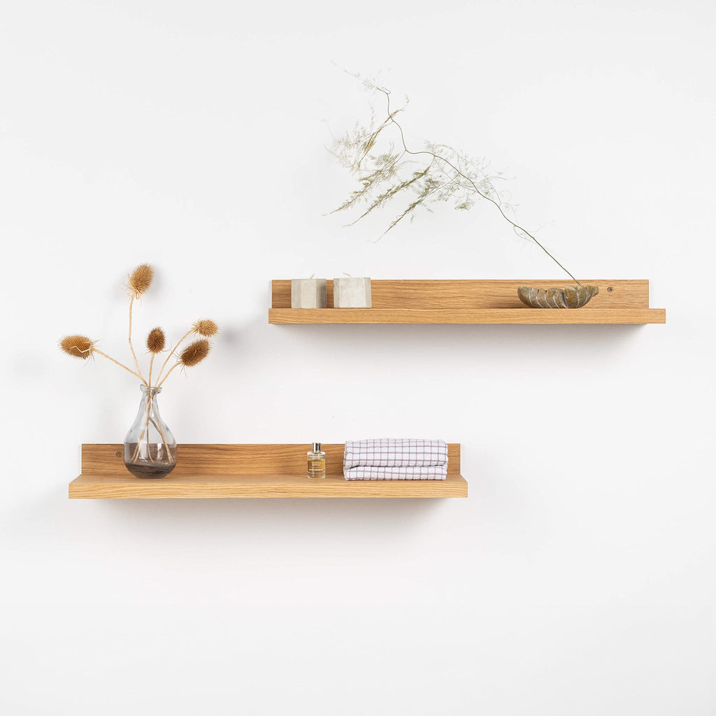 Two natural solid oak wood floating shelves mounted on a minimalist living room wall