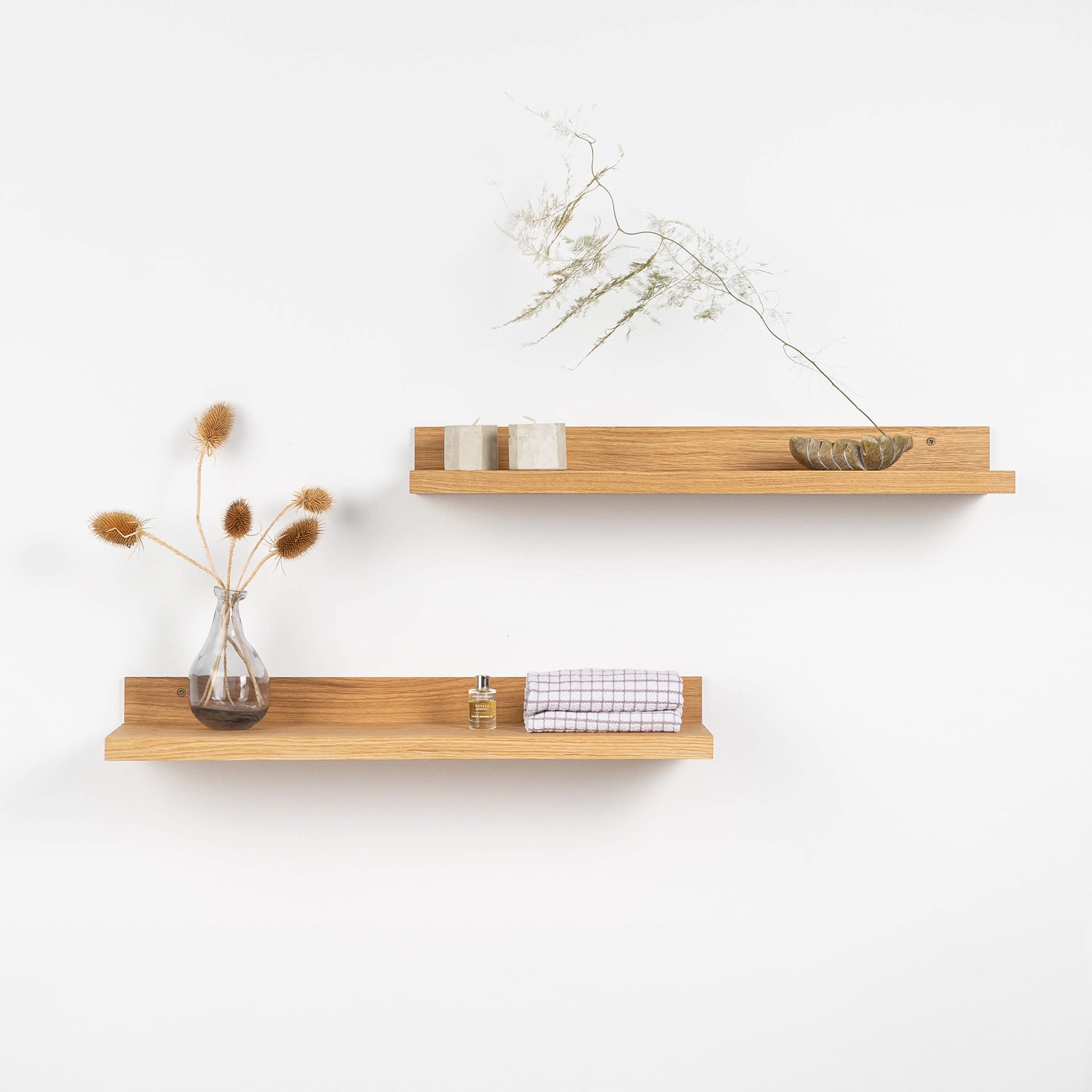 Two natural solid oak wood floating shelves mounted on a minimalist living room wall