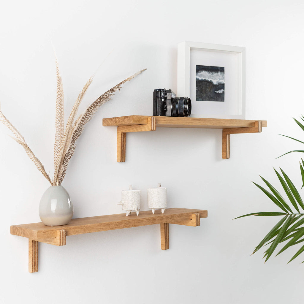 Two natural oak wood floating wall shelves with minimal home decor items and plants