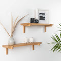 Two natural oak wood floating wall shelves with minimal home decor items and plants