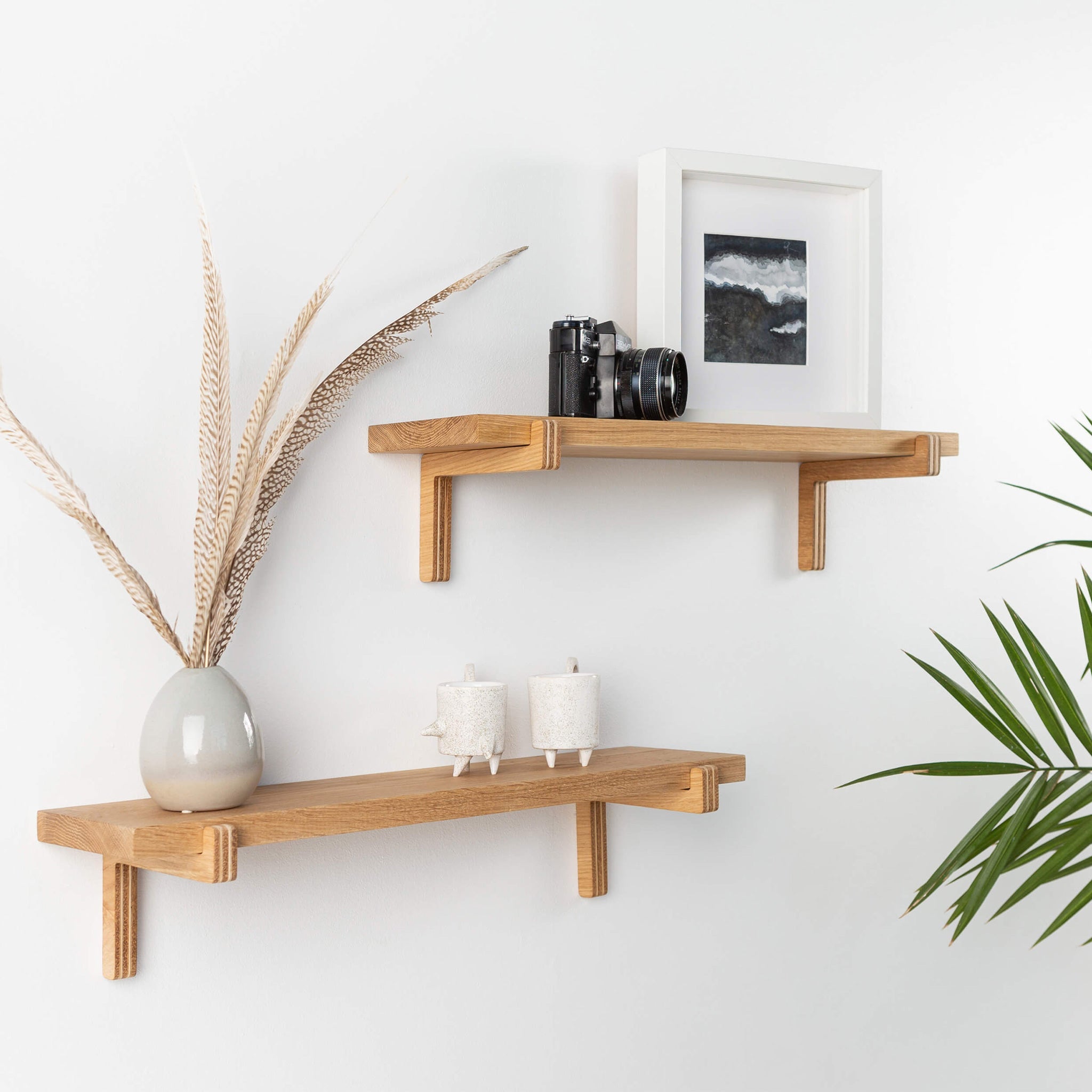 Two natural oak wood floating wall shelves with minimal home decor items and plants
