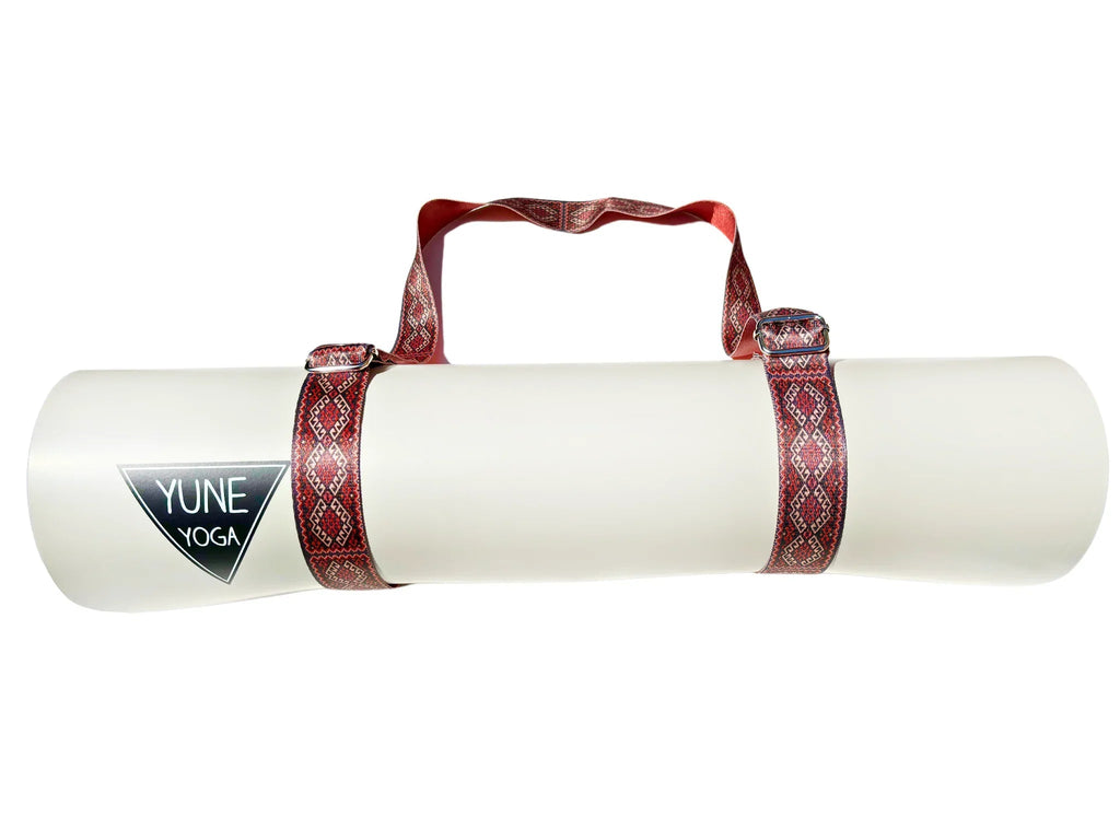 Warm red organic cotton yoga strap with metal D-ring buckles rolled up for studio practice — view 4